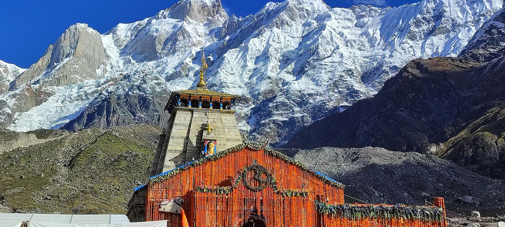 The stone temple at Kedarnath standing below a wall of snow-covered Himalayan peaks.